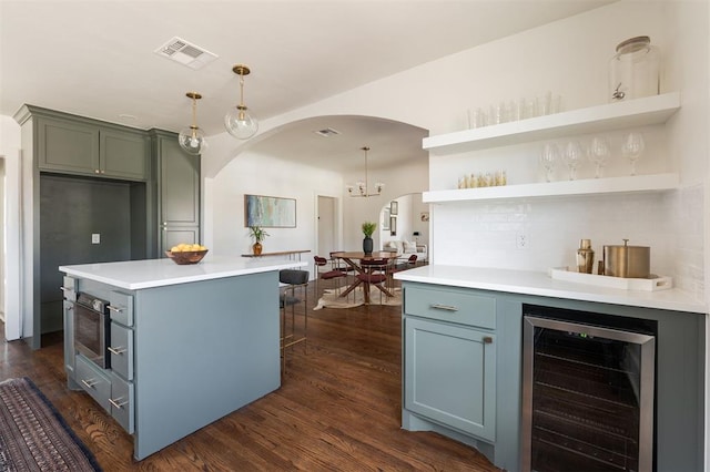 kitchen with a center island, dark hardwood / wood-style flooring, hanging light fixtures, and beverage cooler