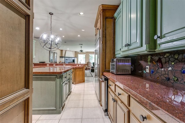 kitchen featuring tasteful backsplash, ceiling fan with notable chandelier, light tile patterned floors, decorative light fixtures, and green cabinetry