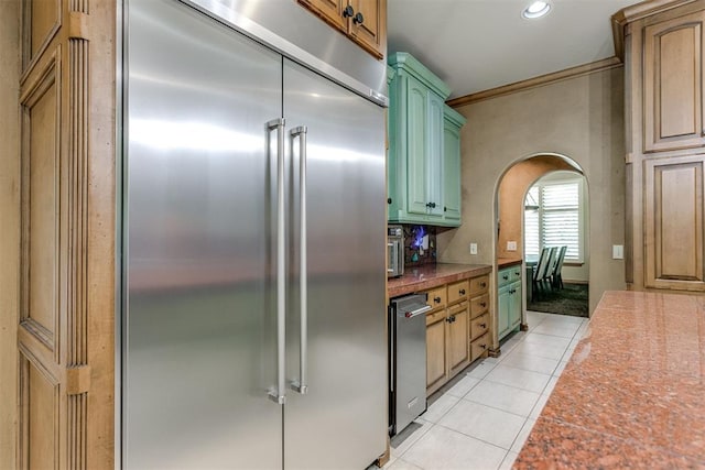 kitchen with stainless steel built in refrigerator, green cabinets, and light tile patterned flooring