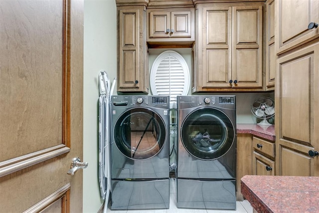 clothes washing area with cabinets, independent washer and dryer, and tile patterned floors