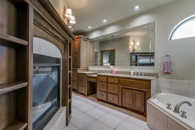 bathroom featuring tile patterned flooring, vanity, and a relaxing tiled tub