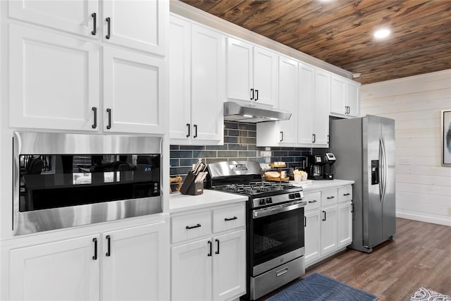 kitchen with white cabinets, appliances with stainless steel finishes, dark hardwood / wood-style flooring, and wooden walls