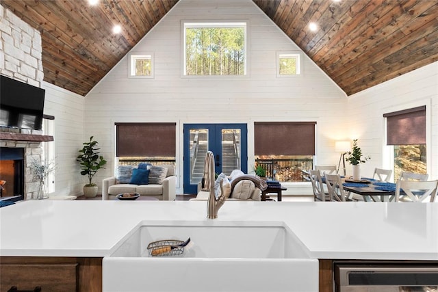 kitchen featuring a stone fireplace, sink, high vaulted ceiling, and wooden ceiling