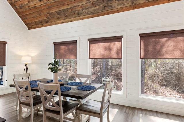 dining area with dark hardwood / wood-style floors, wooden ceiling, wooden walls, and vaulted ceiling