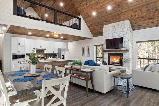 living room with dark hardwood / wood-style flooring, an outdoor stone fireplace, wooden walls, high vaulted ceiling, and wooden ceiling