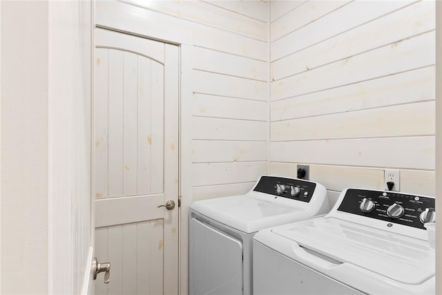 laundry room featuring washer and dryer and wood walls