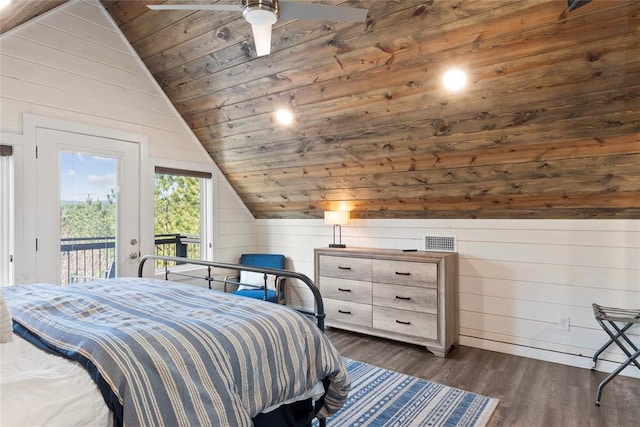 bedroom with wood walls, dark wood-type flooring, access to outside, vaulted ceiling, and ceiling fan