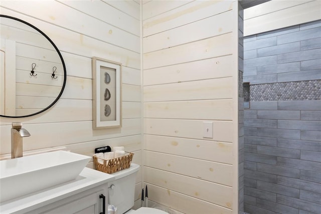 bathroom with vanity, toilet, and wood walls