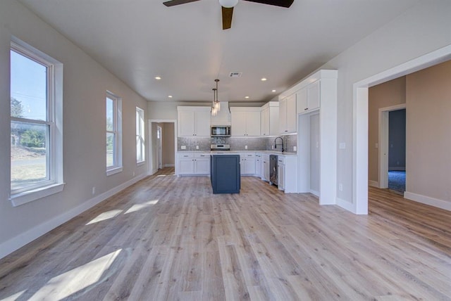 kitchen featuring appliances with stainless steel finishes, light hardwood / wood-style flooring, white cabinetry, and pendant lighting