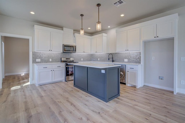 kitchen with white cabinets, decorative light fixtures, and stainless steel appliances