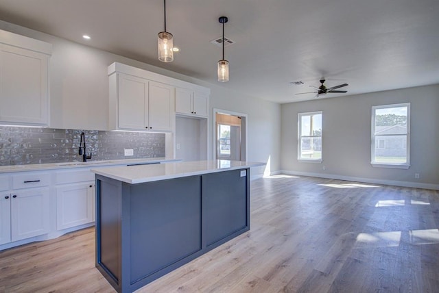 kitchen with white cabinets, light hardwood / wood-style flooring, hanging light fixtures, and sink