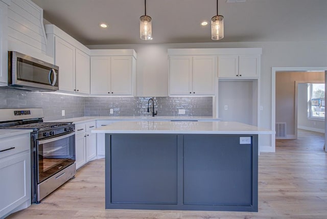 kitchen featuring pendant lighting, light wood-type flooring, stainless steel appliances, and a center island