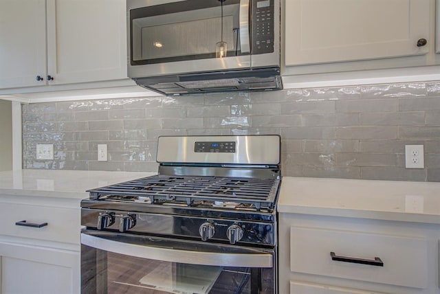 kitchen with white cabinets, appliances with stainless steel finishes, tasteful backsplash, and light stone counters