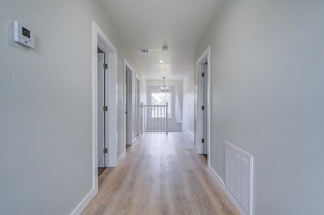 corridor featuring an inviting chandelier and light wood-type flooring