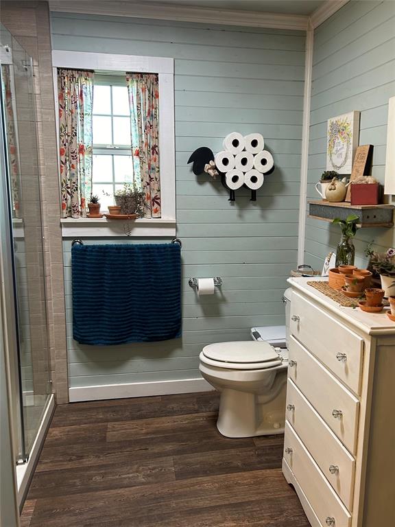 bathroom with hardwood / wood-style flooring, toilet, and wooden walls