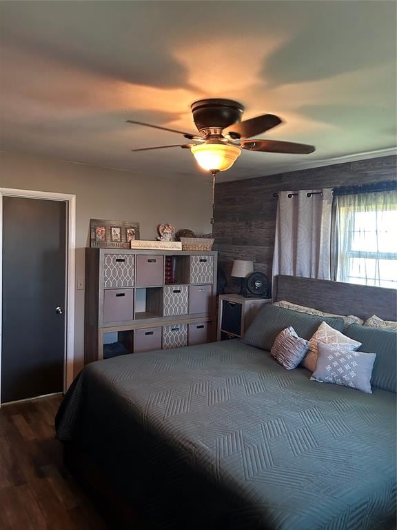 bedroom with hardwood / wood-style flooring, ceiling fan, and wood walls