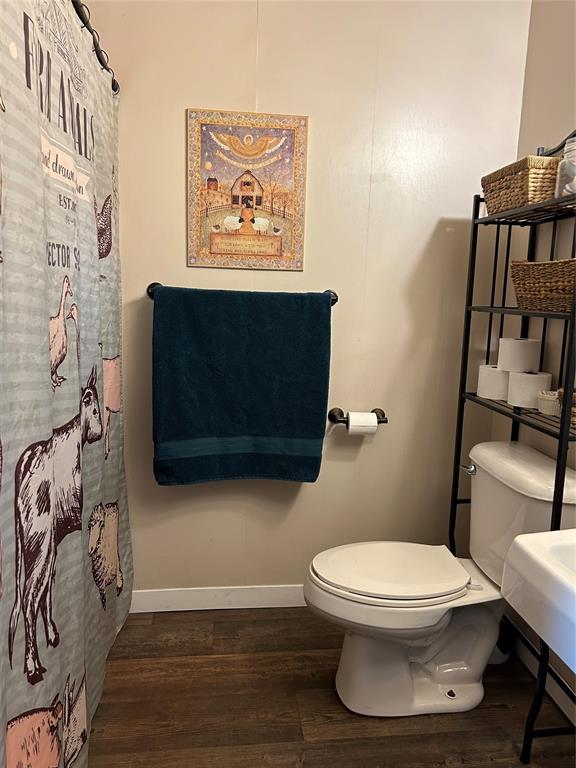 bathroom featuring hardwood / wood-style floors, curtained shower, and toilet