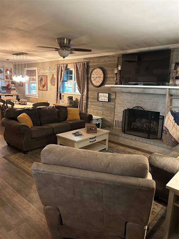 living room featuring hardwood / wood-style flooring, ceiling fan, wood walls, and a fireplace