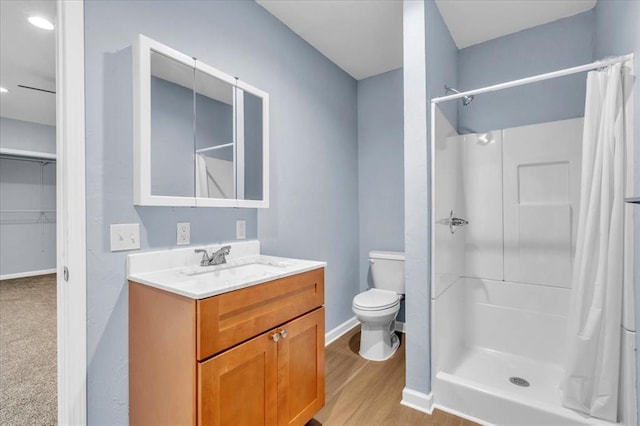 bathroom with hardwood / wood-style floors, vanity, curtained shower, and toilet