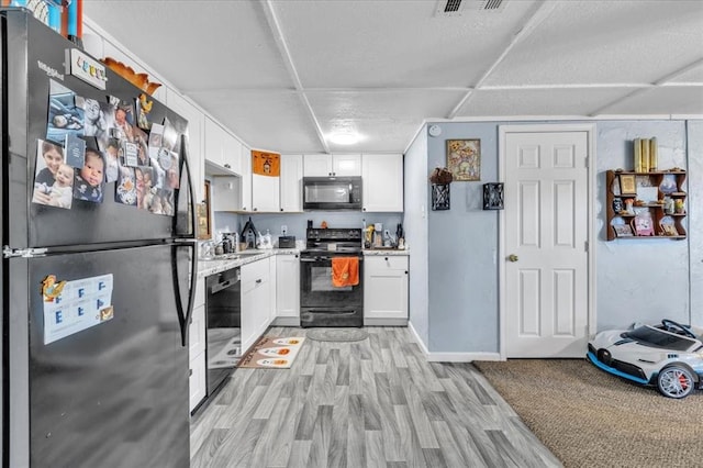 kitchen featuring light wood-type flooring, white cabinetry, and black appliances