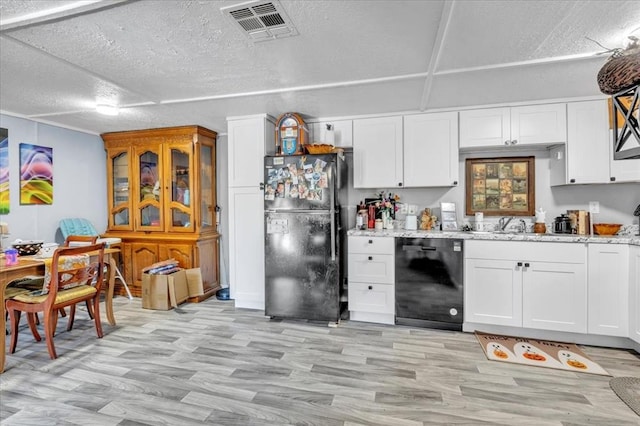 kitchen with light stone counters, white cabinets, black appliances, and light wood-type flooring