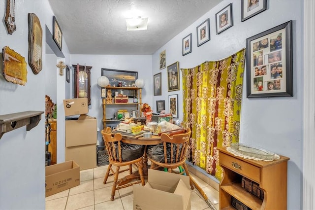 dining area featuring lofted ceiling, light tile patterned floors, and a textured ceiling