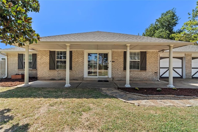 back of house featuring covered porch, a garage, and a lawn