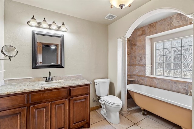 bathroom featuring a washtub, tile patterned flooring, decorative columns, toilet, and vanity