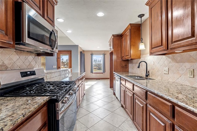 kitchen with light stone countertops, tasteful backsplash, stainless steel appliances, sink, and hanging light fixtures