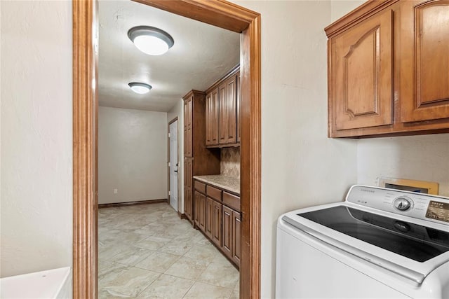 clothes washing area with washer / clothes dryer and cabinets