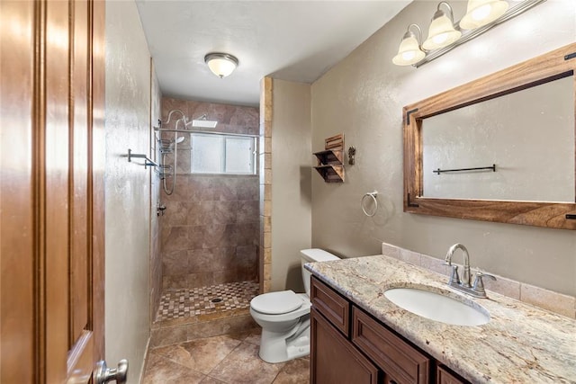 bathroom featuring a tile shower, vanity, toilet, and tile patterned floors