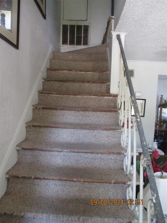 stairs featuring a textured ceiling