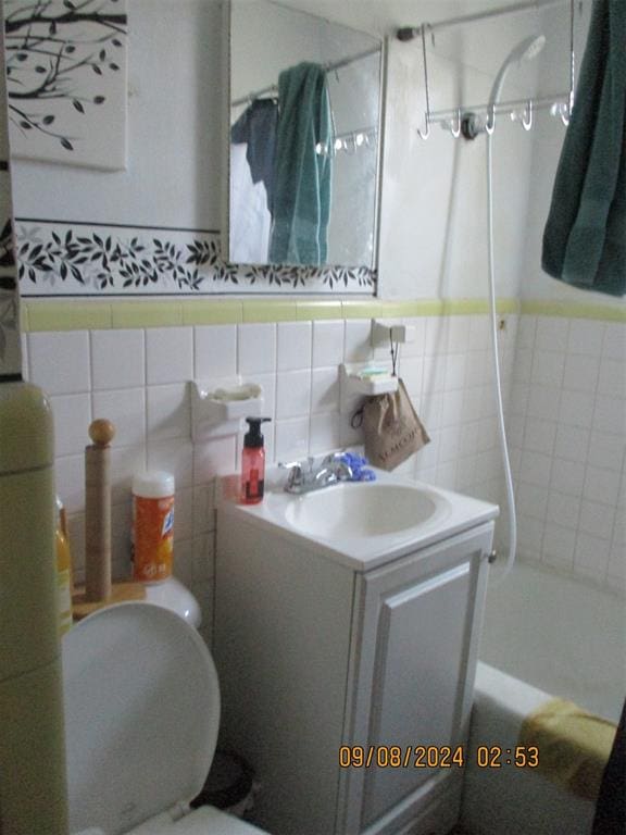 full bathroom with vanity, toilet, tile walls, and tiled shower / bath combo