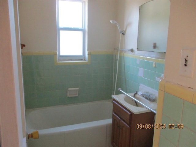 bathroom featuring vanity, tiled shower / bath, and tile walls