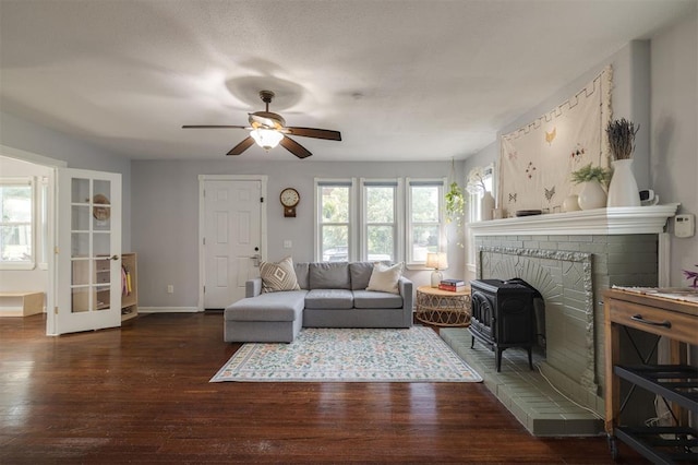 living room featuring a wood stove, ceiling fan, and dark wood-type flooring