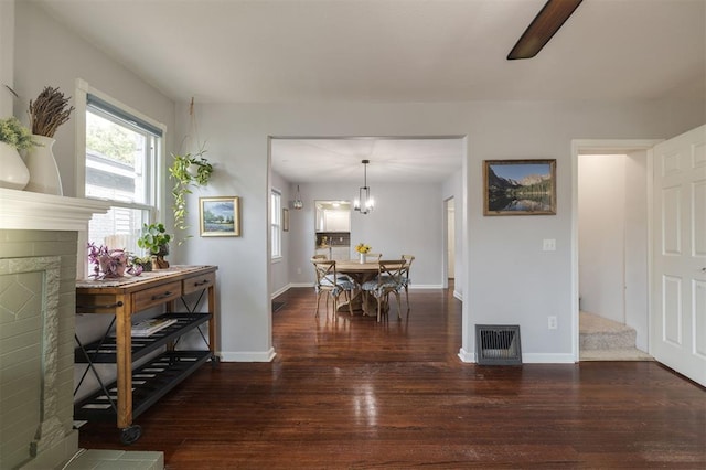 dining area with a notable chandelier, dark hardwood / wood-style flooring, and a fireplace