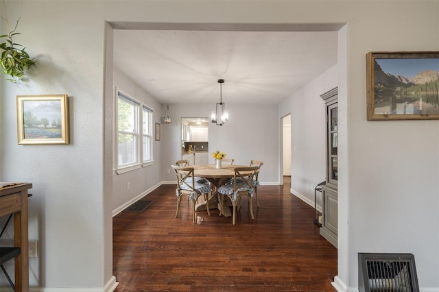 dining space with dark wood-type flooring and a chandelier