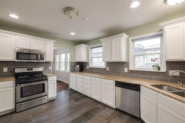 kitchen with sink, dark hardwood / wood-style flooring, light stone counters, white cabinetry, and stainless steel appliances