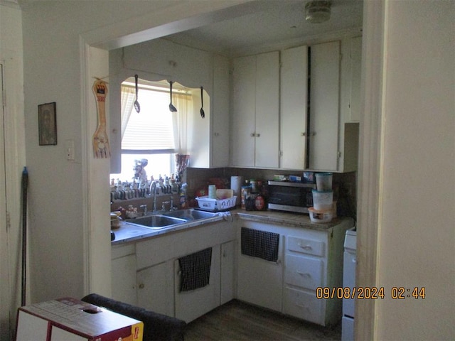 kitchen with wood-type flooring, white cabinetry, and sink