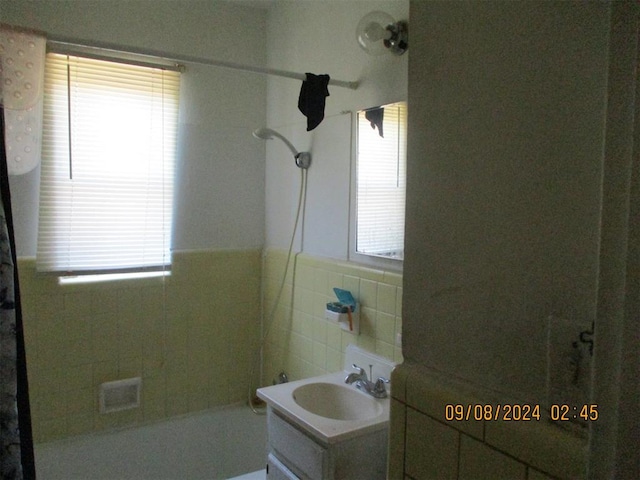 bathroom with shower / tub combination, vanity, and tile walls