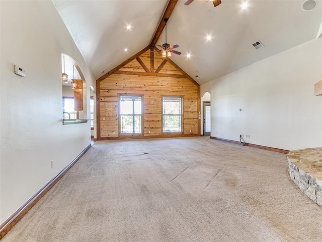 unfurnished living room with ceiling fan, beam ceiling, carpet floors, and high vaulted ceiling