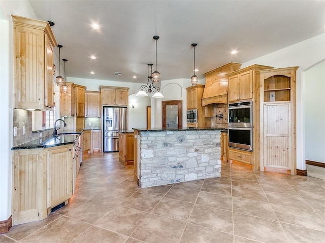 kitchen with custom exhaust hood, appliances with stainless steel finishes, tasteful backsplash, decorative light fixtures, and a kitchen island