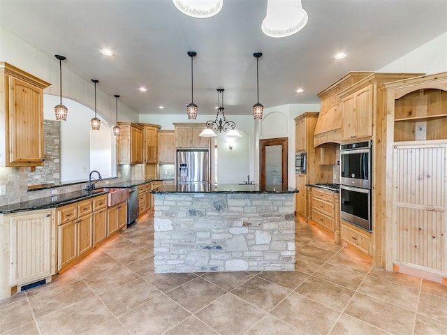 kitchen with decorative backsplash, light brown cabinets, decorative light fixtures, and appliances with stainless steel finishes