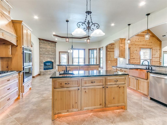 kitchen with wood walls, pendant lighting, a fireplace, a kitchen island, and appliances with stainless steel finishes