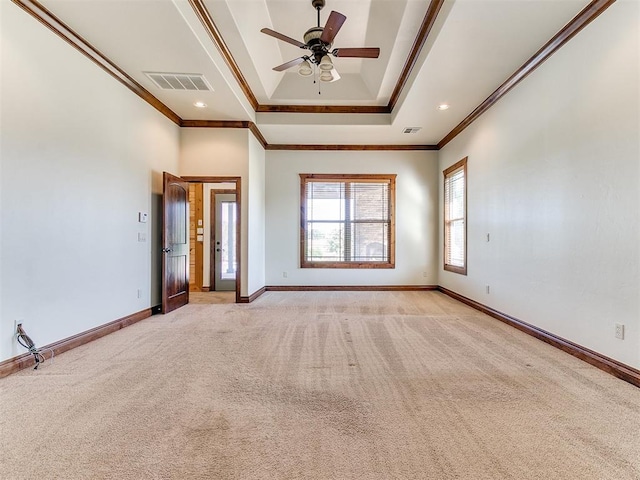 carpeted empty room with a raised ceiling, ceiling fan, and ornamental molding