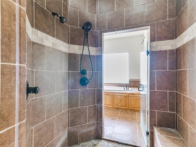 bathroom featuring tile patterned floors, sink, tiled shower, and tile walls