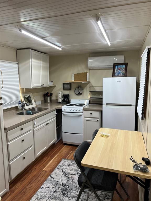 kitchen with white cabinets, dark hardwood / wood-style floors, white appliances, and a wall unit AC