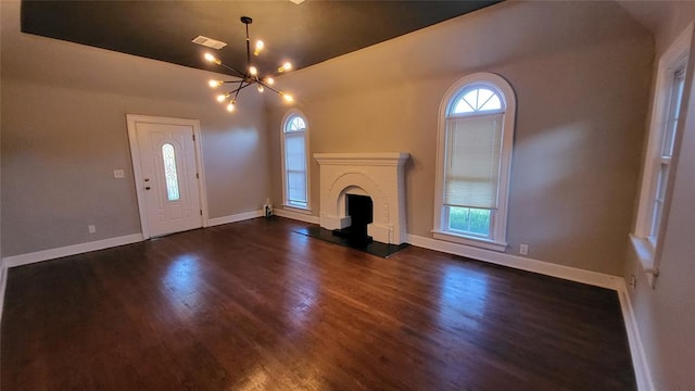 unfurnished living room featuring dark hardwood / wood-style flooring, lofted ceiling, and a chandelier