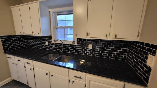 kitchen featuring backsplash, dark stone countertops, white cabinetry, and sink