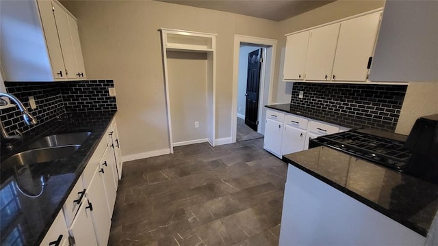 kitchen featuring white cabinets, black stove, backsplash, and sink